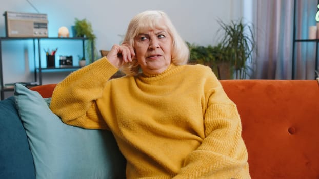 Sad lonely senior woman sits at home looks pensive thinks over life concerns, bankruptcy, crisis, burnout. Elderly alone pensioner having problem, break up, depression, feeling bad annoyed. Retirement