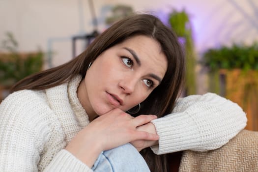 Sad lonely young woman sitting at home room looks pensive thinks over life concerns or unrequited love suffers from unfair situation. Alone girl problem break up, depressed feeling bad annoyed burnout