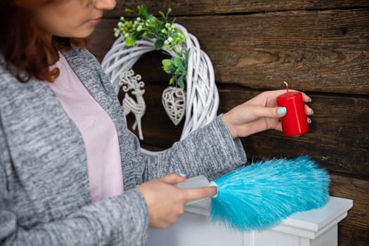 Under each object must be thoroughly cleaned to make the whole room sparkle for Christmas. The girl holds a red candle in her hand.