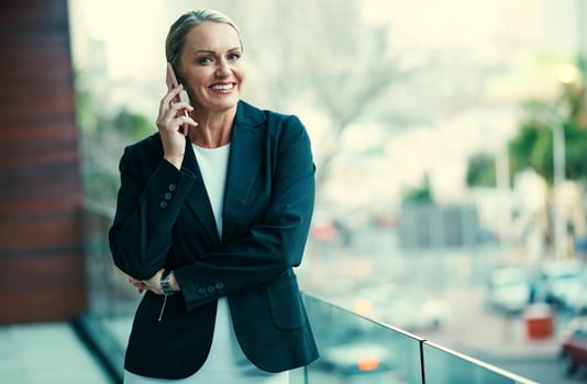 I like what Im hearing. Portrait of a mature businesswoman standing outside on the balcony of an office and using a mobile phone