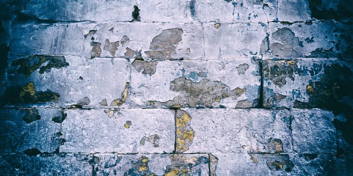 An old white brick wall with chipped paint. Vintage camera effect added to image