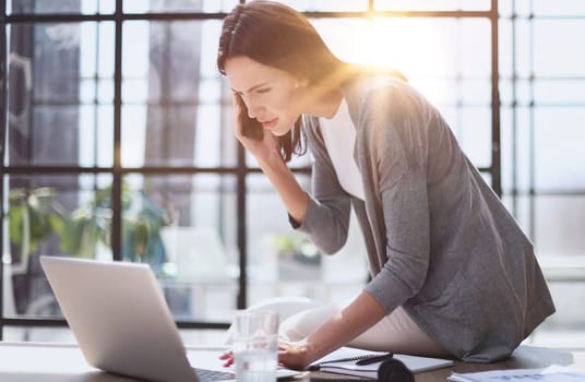 Businesswoman sitting in office, talking on the phone