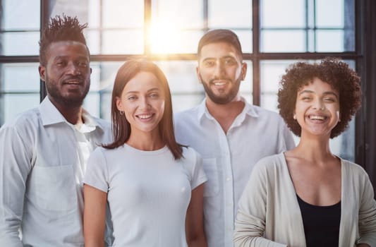 Portrait of successful creative business team looking at camera and smiling. Diverse business people standing together at startup.