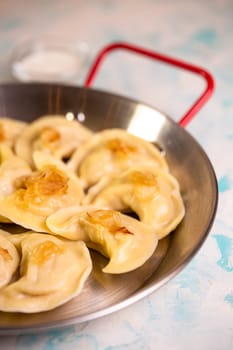 dumplings with potatoes and sour cream in a frying pan.