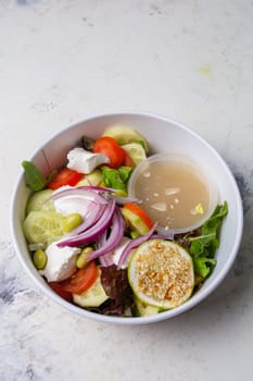 vegetable salad with cheese and sauce on a white background top view.