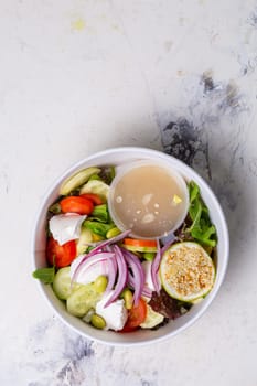 vegetable salad with cheese and sauce on a white background top view.