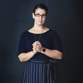 Success is a product of hard work, not luck. Studio portrait of a corporate businesswoman posing against a dark background