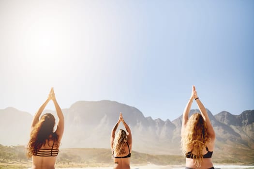 Yoga is always a good idea. Rearview shot of three young women practising yoga on the beach