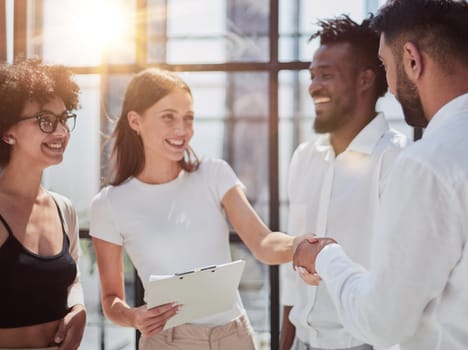 Glad to work with you. Young modern men in smart casual wear shaking hands and smiling while working in the creative office