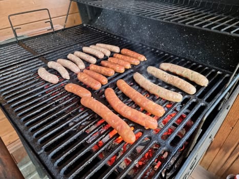 Delicious german sausages sizzling over the coals on barbecue grill