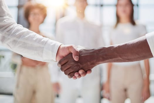 Glad to work with you. Young modern men in smart casual wear shaking hands and smiling while working in the creative office