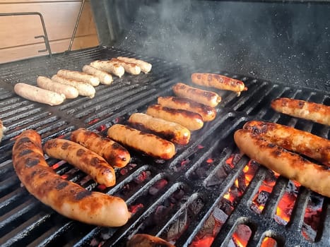 Delicious german sausages sizzling over the coals on barbecue grill