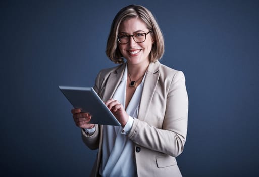 Its an invaluable resource. Studio portrait of an attractive young corporate businesswoman using a tablet against a dark background