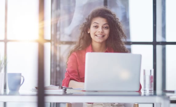 Portrait of Young Successful Caucasian Businesswoman Sitting at Desk Working on Laptop Computer in City Office