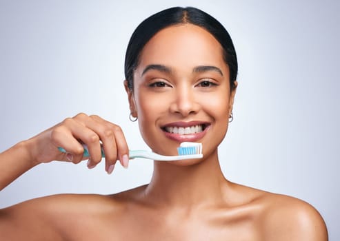 Woman, brushing teeth and studio portrait with smile for self care, dental wellness or health by white background. Girl, dentistry model and toothbrush with toothpaste, product and happy for cleaning.