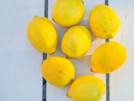Juicy ripe flying yellow lemons, green leaves on light gray background. Creative food concept. Tropical organic fruit citrus vitamin C.