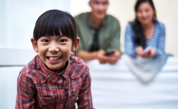 Being with her family brings the biggest smiles. Portrait of a little girl relaxing with her family at home