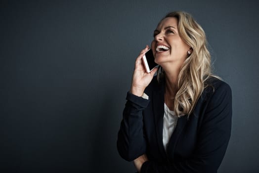 Sounds like shes made another success. Studio shot of a mature businesswoman talking on a cellphone against a grey background