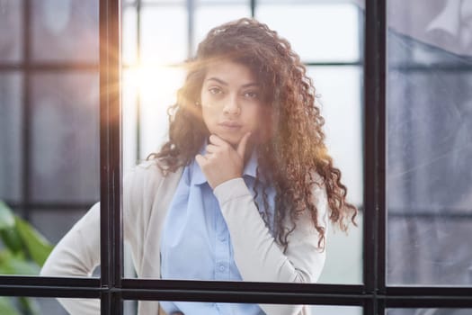 from behind the glass. young business woman thinking about something