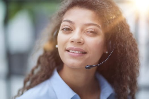 Beautiful smiling woman consultant in headphones with a microphone. Remote work from home.