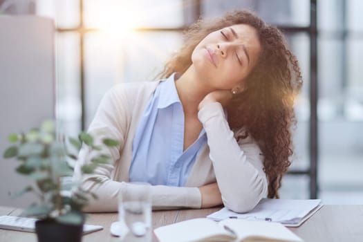Businesswoman with headache sitting at the table in the office