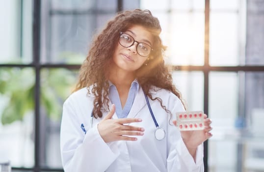 Portrait of young female doctor in white coat at workplace