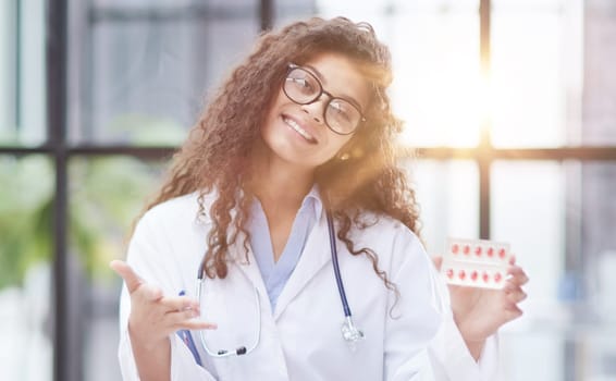Portrait of young female doctor in white coat at workplace