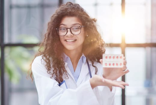 Portrait of young female doctor in white coat at workplace
