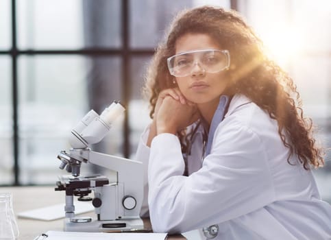 Young woman in biological laboratory. Attractive young female scientis. Scientist using a microscope in a laboratory