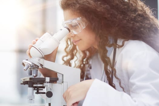 Young woman in biological laboratory. Attractive young female scientis. Scientist using a microscope in a laboratory