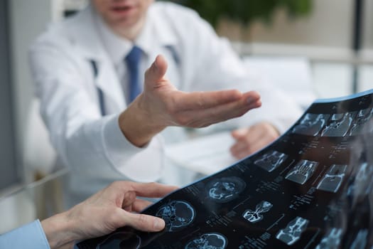 Young man looking at one of x-ray results being shown by his doctor