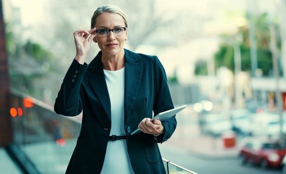 Ready for whatever business has in store. Portrait of a mature businesswoman standing outside on the balcony of an office and holding a digital tablet