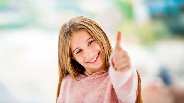 Happy school girl showing thumb up