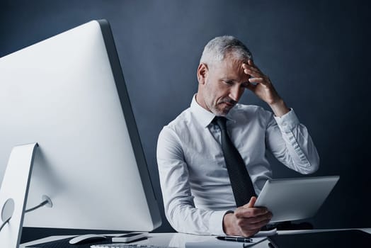 Hes hit a bit of an obstacle. a mature businessman looking stressed working on his tablet