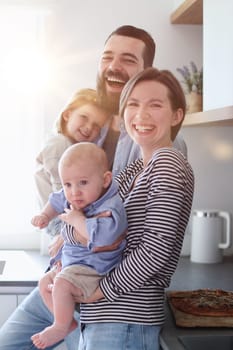 Family of 4 posing in the kitchen smiling and happy