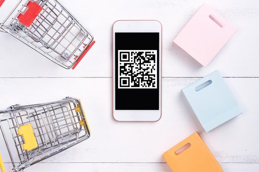 Abstract online shopping, mobile payment with QR code design concept element, colorful cart, paper bag on wooden table background, top view, flat lay