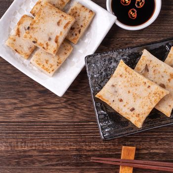 Delicious turnip cake, Chinese traditional radish cake in restaurant with soy sauce for new year's dishes, close up, copy space, top view, flat lay.