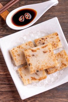 Delicious turnip cake, Chinese traditional radish cake in restaurant with soy sauce for new year's dishes, close up, copy space, top view, flat lay.