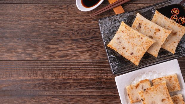 Delicious turnip cake, Chinese traditional radish cake in restaurant with soy sauce for new year's dishes, close up, copy space, top view, flat lay.