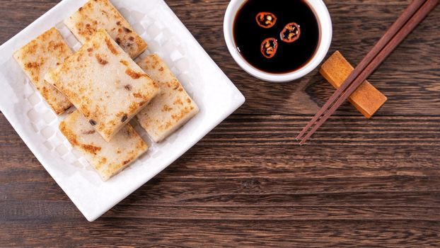 Delicious turnip cake, Chinese traditional radish cake in restaurant with soy sauce for new year's dishes, close up, copy space, top view, flat lay.