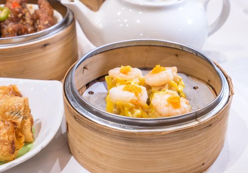 Siu Mai, one of Dim Sum yum cha, pork and shrimp steamed dumplings on restaurant house white background table for breakfast, lifestyle, close up.