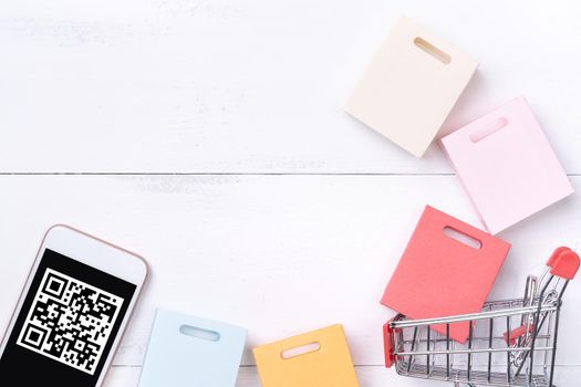 Abstract online shopping, mobile payment with QR code design concept element, colorful cart, paper bag on wooden table background, top view, flat lay