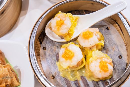 Siu Mai, one of Dim Sum yum cha, pork and shrimp steamed dumplings on restaurant house white background table for breakfast, lifestyle, close up.