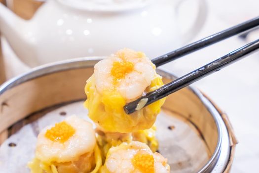 Siu Mai, one of Dim Sum yum cha, pork and shrimp steamed dumplings on restaurant house white background table for breakfast, lifestyle, close up.