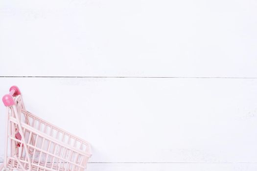 Abstract design element,annual sale,shopping season concept,mini cart with colorful paper bag on white wooden table background,top view,flat lay