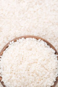 Raw white polished milled edible rice crop on white background in brown bowl, organic agriculture design concept. Staple food of Asia, close up.