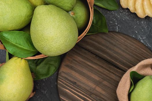 Fresh peeled pomelo, pummelo, grapefruit, shaddock on dark background in bamboo basket. Autumn seasonal fruit, top view, flat lay, tabletop shot.