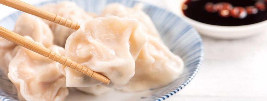 Fresh, delicious boiled pork, shrimp gyoza dumplings on white background with soy sauce and chopsticks, close up, lifestyle. Homemade design concept.