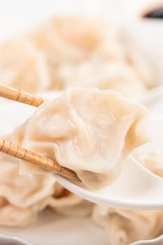 Fresh, delicious boiled pork, shrimp gyoza dumplings on white background with soy sauce and chopsticks, close up, lifestyle. Homemade design concept.