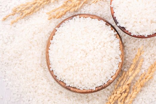 Raw white polished milled edible rice crop on white background in brown bowl, organic agriculture design concept. Staple food of Asia, close up.